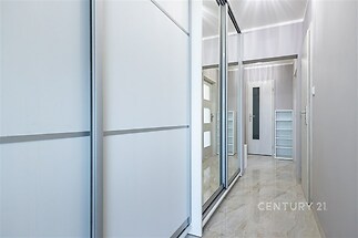 Úzká chodba s dlažbou a vestavěnými skříněmi, moderní provedení, světlé barvy, skleněné dveře propouštějí přirozené světlo