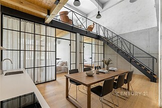 Moderní kuchyň s parketovou podlahou a vysokými stropy, světlé omítky a ocelové schodiště, přechod do prostorné ložnice a galerie