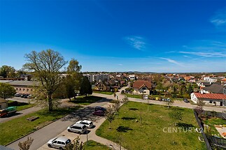 Výhled na klidnou rezidenční čtvrť s parkovou zelení, moderními domy a čistou ulicí, ideální pro rodinné bydlení.