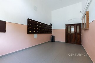 Společná vstupní hala s dlažbou, dřevěnými dveřmi a poštovními schránkami, nabízí světlé prostory v udržovaném stavu.