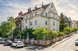 Rohový bytový dům ve městě, cihlová fasáda, velká okna, stylová zahrada, v klidné lokalitě.