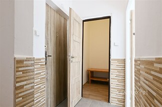 Vstupní hala s keramickou dlažbou, světlými dřevěnými dveřmi a moderním obložením stěn, přináší elegantní a praktický design.