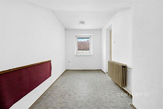 Chodba s dlažbou, bílými stěnami a oknem, obsahuje radiátor, vhodná pro úpravu.