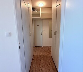 Vstupní chodba s vestavěnými skříněmi, moderní dlažbou a světlou výmalbou nabízí praktické úložné prostory i elegantní vzhled.