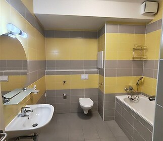 Koupelna s moderní dlažbou, světlá keramika, vanou a praktickým umyvadlem, ideální pro pohodlné bydlení.