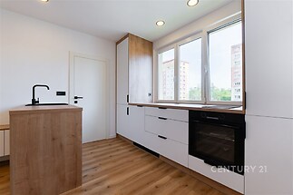 Moderní kuchyň s dřevěnými prvky, parketová podlaha, vestavěné spotřebiče, velká okna poskytují dostatek světla