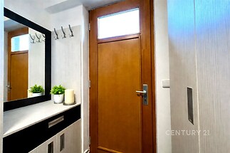 Vstupní hala s dřevěnými dveřmi, vestavěnou skříní a moderními úložnými prostory. Světlý interiér s ozdobným zrcadlem a dekorativními prvky.