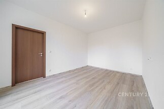 Prázdný pokoj s moderní parketovou podlahou, dřevěnými dveřmi a světlými stěnami, ideální pro personalizaci a vytvoření útulného prostředí