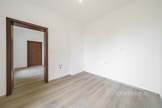 Prázdná místnost s parketovou podlahou a bílými stěnami, moderní výplň dveří, vhodná k přizpůsobení, ideální pro rekonstruovaný byt.