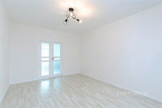 Světlý pokoj s parketovou podlahou, moderní dveře s matným sklem a minimalistické osvětlení, ideální pro vytvoření útulného interiéru.