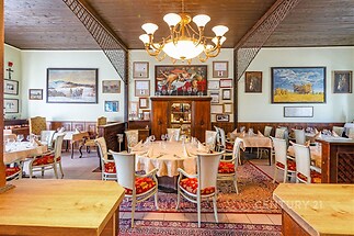Restaurace s dřevěným stropem nabízí útulnou atmosféru, vintage dekorace a elegantní dřevěný nábytek, ideální pro příjemné stolování.