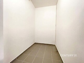 Prázdná místnost s dlažbou, bílými stěnami a moderním vzhledem, ideální pro šatnu nebo úložný prostor.