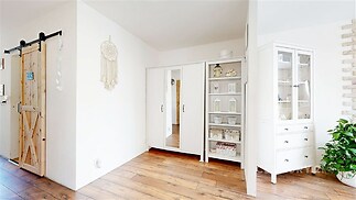 Vstupní hala s dřevěnou podlahou, vestavěnými skříněmi a moderním interiérem, zdůrazňuje světlé a vzdušné prostředí.