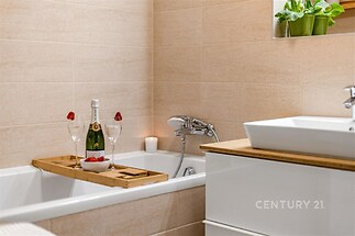 Koupelna s moderní dlažbou, vanou a dřevěnými detaily, nabízí elegantní atmosféru pro relaxaci.