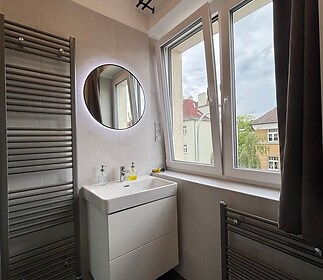 Moderní koupelna s velkými okny, dlažbou a stylovým umyvadlem; skvělé prosvětlení a praktické řešení úložných prostor.