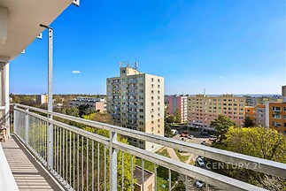Balkon s výhledem na městskou zástavbu, vybavený kovovým zábradlím, nabízí panoramatický pohled a klidnou atmosféru pro relaxaci