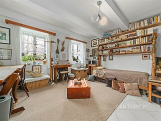 Světlý obývací pokoj s velkými okny, dřevěnými detaily a vestavěnými policemi, vybavený moderní dlažbou a příjemnými doplňky.