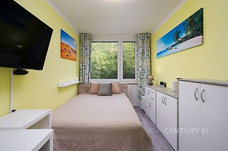 Světlá ložnice s velkými okny, vestavěnými skříněmi a moderním dekorem, nabízí útulný prostor pro relaxaci.