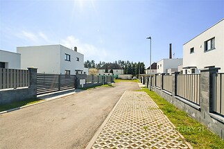Moderní rezidenční ulice s novostavbami, minimalistický design, oplocení z kovu, klidná lokalita v blízkosti přírody