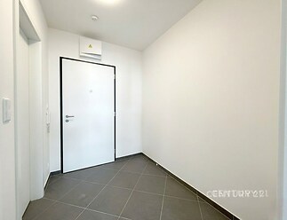 Vstupní chodba s dlažbou, moderní bílá výmalba a bezpečnostními dveřmi, ideální pro rekonstruovaný byt.