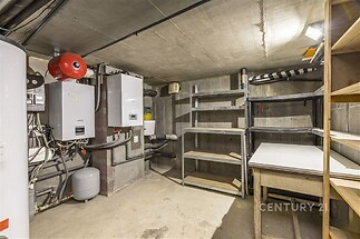 Praktická technická místnost s betonovou podlahou, vestavěnými policemi a moderními kotly, ideální pro skladování a instalaci techniky.