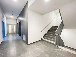 Světlé schodiště s moderní dlažbou a nerezovým zábradlím, minimalistický design a nové povrchy, prostorná chodba s čistými liniemi.