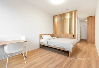 Prostorná ložnice s parketovou podlahou, dřevěnou příčkou a moderním nábytkem, ideální pro komfortní bydlení.