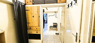 Chodba s dlažbou, dřevěnými úložnými prostory a bílými stěnami. Disponuje vestavěnými skříněmi a moderním, světlým interiérem.