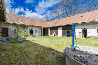 Venkovní dvůr s travnatou plochou, starými kamennými zdi a šindelovou střechou, vhodný pro rekonstrukci a adaptaci na moderní bydlení.