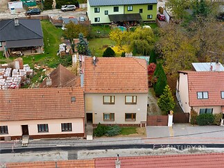 Středně velký rodinný dům s červenou střešní krytinou, moderní omítkou a zahradou. Nachází se v klidné rezidenční čtvrti.