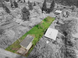 Pozemek s výhledem na okolní krajinu, vzrostlé stromy a malá budova, vhodný pro výstavbu. Tichá lokalita s přírodním prostředím.