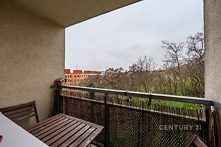 Balkón s výhledem do přírody, vybavený dřevěným nábytkem, působí útulně. Skvělá lokalita pro relaxaci, ideální pro moderní bydlení.