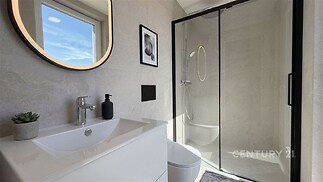 Moderní koupelna s velkou sprchou, světlé dlaždice a elegantní zrcadlo, minimalistický design přináší svěžest a styl.