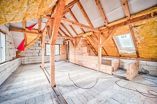 Prostorné podkroví s dřevěnými trámy, přípravou na rekonstrukci, velká okna, přirozené světlo a odhalené cihlové stěny