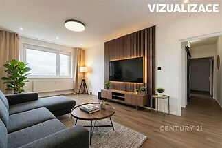 Světlý obývací pokoj s parketovou podlahou a velkými okny, moderní design, dřevěný nábytek, útulné osvětlení, minimalistický styl.