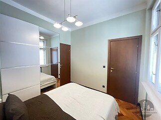 Prostorná ložnice s parketovou podlahou, vestavěné skříně a velkými okny, moderní design a světlé odstíny vytváří příjemný interiér.