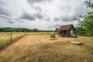 Rozlehlá zahrada s dřevěným zahradním domkem, oplocení a klidná lokalita, ideální pro rekreační využití nebo pěstování.