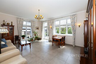 Světlý obývací pokoj s velkými okny, dlažba a klasický interiér, prostorný a vzdušný design ideální pro rodinné setkání