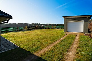 Rozlehlá zahrada s dobře udržovaným trávníkem, samostatná garáž a moderní oplocení, klidné okolí nabízí ideální místo pro rodinný život.