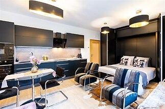 Moderní garsoniéra s parketovou podlahou, elegantní černou kuchyní a vestavěnou postelí, působí světlým a prostorným dojmem.