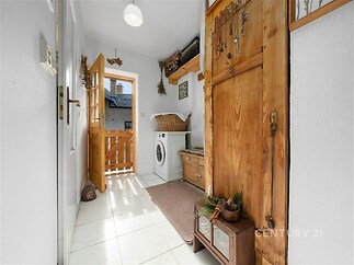 Světlá vstupní chodba s dlažbou, dřevěnými dveřmi a dekoracemi. Obsahuje místo pro pračku a vestavěné dřevěné skříně.