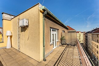 Střešní terasa s dlažbou, moderní design a výhledem na městskou architekturu, ideální pro relaxaci a venkovní posezení.
