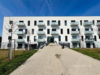 Moderní bytový dům s balkony, minimalistická architektura, světlá fasáda, nový development v klidné lokalitě.