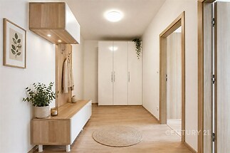 Vstupní hala s moderním dřevěným nábytkem, vestavěnými skříněmi a parketovou podlahou působí světlým a vkusným dojmem.