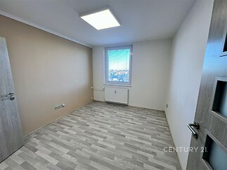 Světlý pokoj s laminátovou podlahou a velkým oknem, moderní dveře, nedávno rekonstruovaný, ideální pro útulné bydlení.