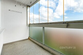 Zasklená lodžie s dlažbou, moderní úprava a posuvné okna nabízí světlý prostor pro relaxaci a výhled na oblohu.