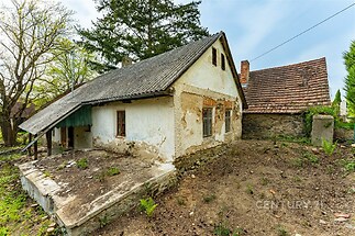 Venkovský dům s kamennou fasádou a šikmou střechou, potřebuje rekonstrukci. Nachází se v klidném prostředí, ideální pro úpravu podle představ.