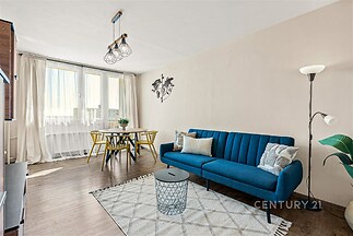 Světlý obývací pokoj s moderním designem, parketová podlaha, velká okna, minimalistický styl, pohodlná sedací souprava, jídelní kout