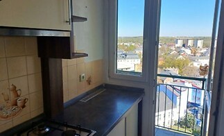 Kuchyň s plynovým sporákem a výhledem na město, dlažba na stěně, světlé moderní provedení s velkým oknem a výhledem z balkonu.