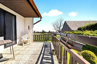 Prostorný balkon s dlažbou, dřevěným zábradlím a výhledem na zahradu; ideální pro relaxaci, světlý a dobře udržovaný prostor.